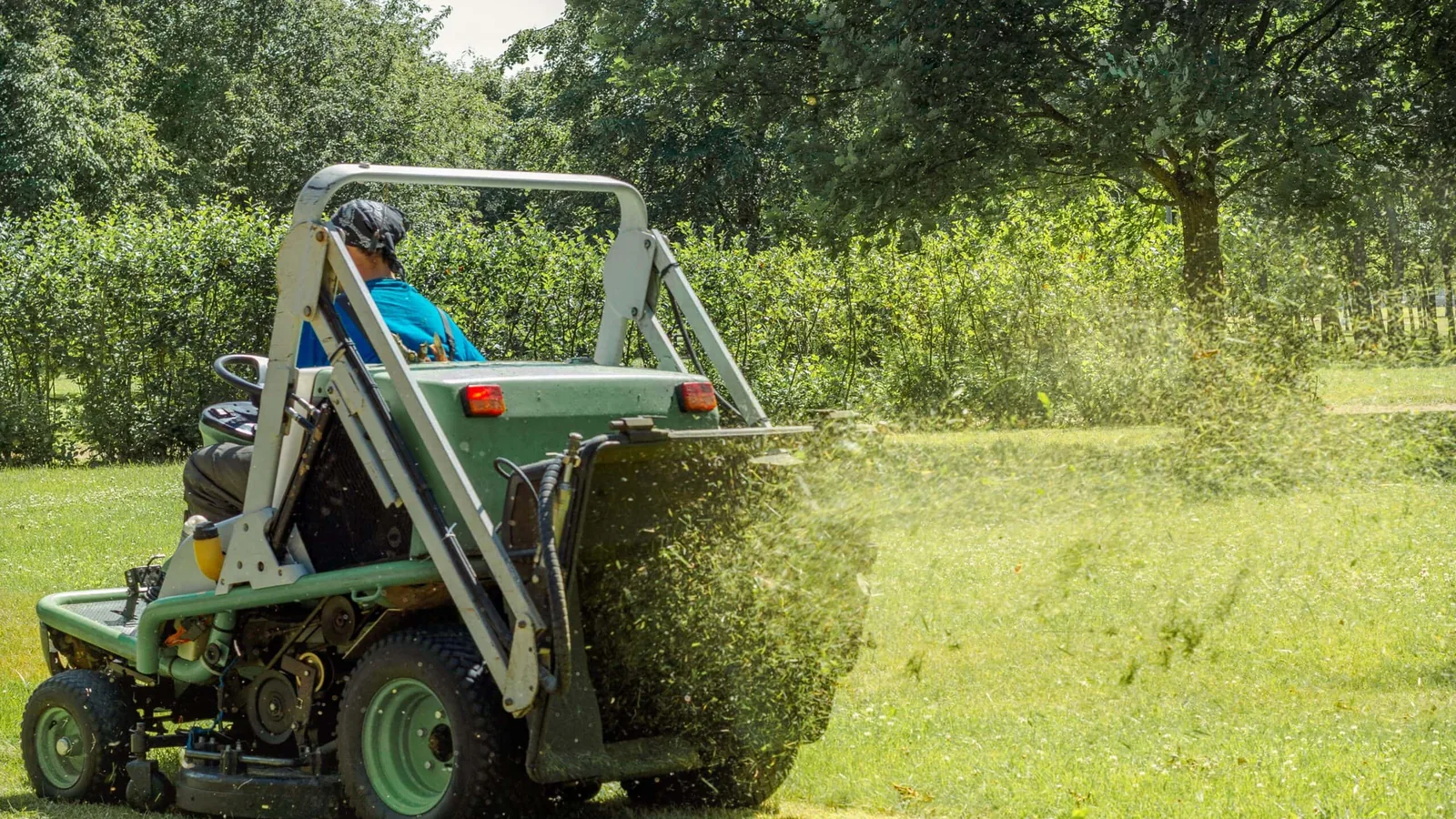 A crew member cutting grass on a ride-on mower